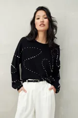 Sweater color beige con cuello redondo y mangas largas. Decorado con perlas sintéticas en forma de rombos.