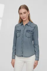 Camisa de jean celeste de manga larga, con cuello clásico, cierre frontal con botones a presión y dos bolsillos con solapa en el pecho.