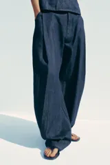 Pantalón de denim azul con pinzas delanteras, tiro medio, cintura con trabillas, bolsillos laterales y traseros.