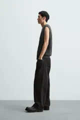 Chaleco negro de punto con cuello en V y cierre frontal con cremallera. Tiene bolsillos de ribete en la cadera y un corte relajado.