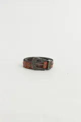 Cinto de cuero color marrón con tachas metálicas plateadas y hebilla labrada estilo western.