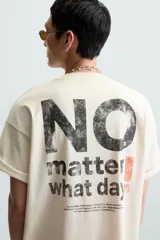 Camiseta color crema de corte cuadrado, con cuello redondo y mangas cortas. Estampado frontal con la frase "no matter what day" en letras pequeñas de color negro.