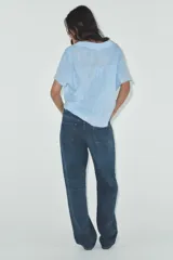 Camisa color gris claro con cuello solapa y escote pico, de manga corta. Presenta un nudo en la parte delantera y cierre frontal con botones.