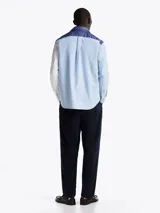 Camisa de manga larga con diseño color block en azul y blanco, confeccionada en algodón Oxford, con cuello abotonado, bolsillo de parche en el pecho, puños redondeados con botón y logo bordado en el bolsillo.