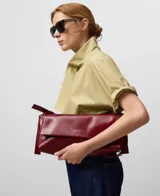 Bolso de hombro tipo baguette color blanco hueso, con textura craquelada y acabado brillante. Cierre magnético con solapa frontal y asa corta regulable.