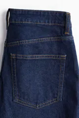 Pantalón de jean azul oscuro, de corte ancho y tobillero, con tiro alto, cinco bolsillos y cierre con botón.