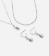 Conjunto de bijouterie plateada que incluye un collar doble, uno con cadena de eslabones y otro con dije de limón con strass, y un par de aros de media argolla con dije de limón con strass.