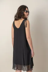 Vestido corto negro de seda con breteles finos anudados en los hombros y escote en V.