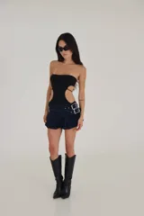 Conjunto de body negro strapless con aberturas laterales y mini falda azul marino con cinturón de hebillas.