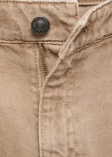 Pantalón de jean color beige, de corte wideleg, tiro bajo, con cinco bolsillos y cierre frontal con cremallera y botón.