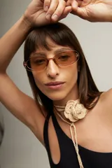 Gargantilla beige tejida a crochet con forma de flor y tiras para atar.