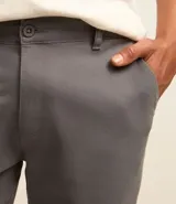 Pantalón de vestir color marrón, de corte recto, con bolsillos laterales y traseros. Se ajusta a la cintura con cinturón de cuero marrón.