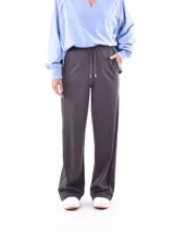 Pantalón deportivo ancho color gris oscuro, con cordón ajustable en la cintura y costura central vertical en la pierna.