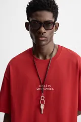 Camiseta roja de corte relajado, cuello redondo y manga corta. Estampado con texto en el frente y la espalda.
