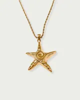 Collar dorado con cadena de eslabones retorcidos y dije de estrella de mar con diseño de espiral en el centro.