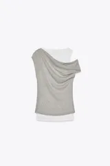 Camiseta blanca con musculosa gris superpuesta con escote asimétrico.