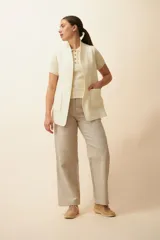 Chaleco color beige, entallado, con solapa, bolsillos plaqué y terminaciones envivadas.