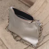 Cartera tipo baguette de cuero color rojo brillante, con correa de cadena plateada.