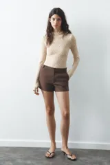 Shorts tiro bajo color negro con bolsillos delanteros. Cierre frontal con cremallera y ganchos metálicos.