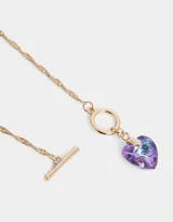 Collar corto dorado con cadena de eslabones retorcidos y dije de corazón de cristal color lila.