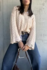 Sweater beige de punto calado con mangas acampanadas.