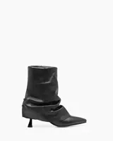 Bota de cuero negro con caña corta arrugada y taco fino.