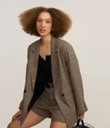 Blazer marrón con estampado de cuadros, corte oversized, cuello en V, manga larga y cierre con dos botones delanteros.