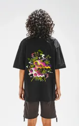 Remera negra oversize de algodón con estampado en la espalda de moléculas y hojas de marihuana en tonos rosa, amarillo y verde.
