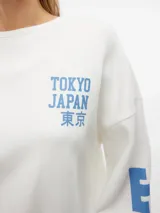 Sudadera blanca de cuello redondo, manga larga y corte oversize. Estampado frontal con la leyenda "Tokyo Japan 東京" en color azul. Diseño con puños y ruedo acanalados.