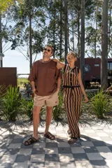 Conjunto tejido de dos piezas con rayas verticales en tonos marrón y negro. Incluye un chaleco sin mangas con botones y un pantalón de corte recto.