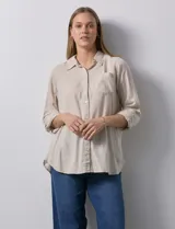 Camisa color beige de lino y rayón, con cuello con solapa, manga 3/4 regulable con presilla y botón, y abertura central con botones.