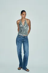 Top plateado con lentejuelas, cuello halter ajustable con lazada y forro interior de tul.