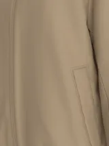 Campera color beige con cierre frontal y cuello alto. Logo de la marca en el pecho.