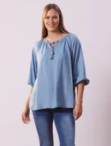Blusa celeste de tencel, marca Marissa Olivia, con cuello a la base, escote en V con aplique de cordel y lazo de ajuste. Manga larga amplia con puño elastizado.