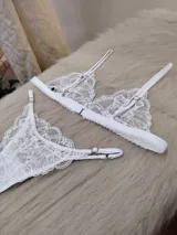 Conjunto de lencería blanco de encaje, compuesto por un bralette triangular con breteles regulables y una tanga regulable de corte less con entrepierna de algodón.