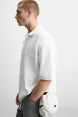Polo blanco de piqué con corte relaxed fit, cuello solapa y cierre frontal con botones.