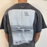 Remera gris con efecto lavado y estampado de una fotografía de la playa en la espalda. Corte oversize.