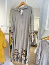 Vestido camisero de lino color gris con botones frontales, corte recto, cuello clásico y mangas largas con puños estampados con animal print.