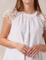 Blusa blanca de crepe marca Liv Los Ángeles, con hombros con aplique en crochet y espalda con abertura ojal y botones.
