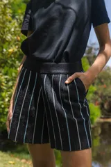 Short tejido negro con lurex y rayas verticales blancas y celestes. Cintura elastizada.