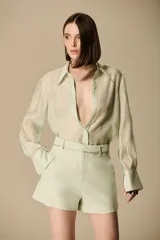 Camisa blanca de seda fluida, con silueta relajada, mangas largas con puño simple y cuello clásico.