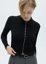 Jersey negro de punto fino con cuello camisero, diseño entallado y botones decorativos.