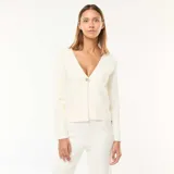 Cárdigan color crema de punto con escote en V, cierre con un botón dorado y mangas largas.