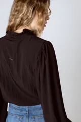 Camisa blanca de mangas largas abullonadas, con cuello mao y cierre frontal con botones.