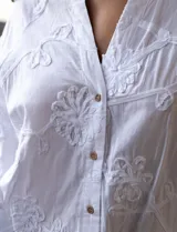 Blusa blanca de algodón bordado, marca Hetser & Orchard. Cuello a la base, escote en V y abertura central con botones. Manga larga amplia.