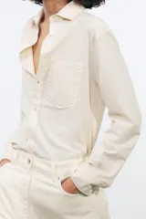 Camisa color crema de algodón y lyocell, con cuello solapa, manga larga con puños y bolsillo de parche en el pecho.