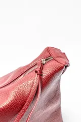 Bolso tipo hobo de cuero sintético color rojo oscuro con textura granulada.