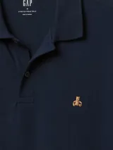 Chomba celeste de piqué con cuello clásico y tapeta de dos botones. Tiene mangas cortas con puños acanalados y logo de un oso bordado en el pecho.