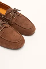 Mocasines náuticos de cuero color marrón, con cordones de cuero y suela de goma.