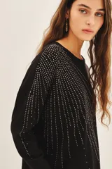 Sweater negro de moldería holgada, liviano y de caída relajada. Con aplicación de tachas termofijadas que expanden desde el hombro hacia el bajo ruedo de forma radial.
